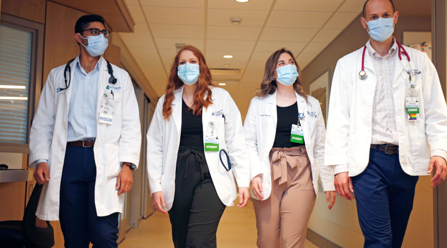 four students walking through a hospital hallway
