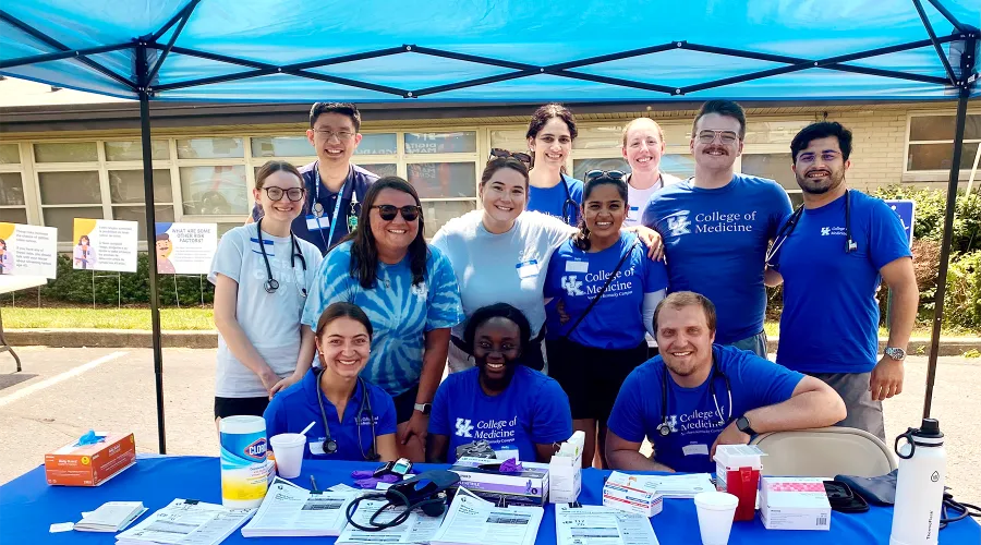 students smiling at an outdoor booth