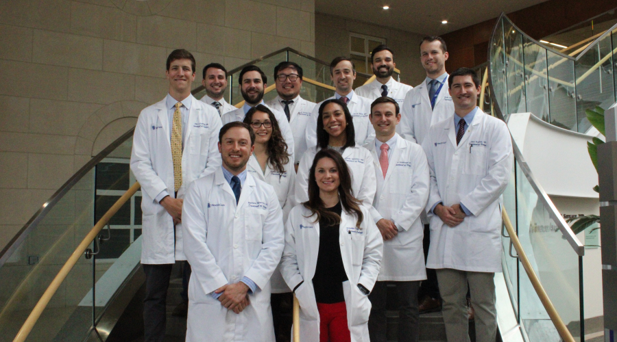 A group of urology residents standing on the stairs in white coats.