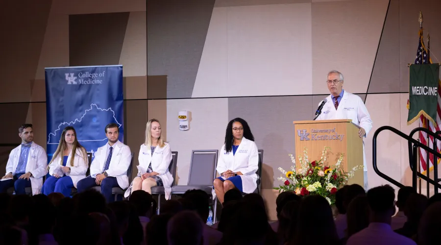 the dean and faculty greeting an audience from a stage