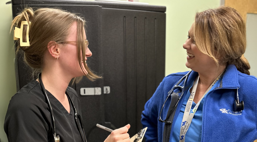 a faculty physician interacting with a student at the clinic