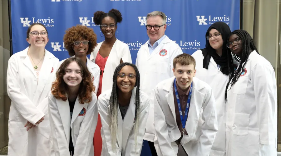 faculty member with young students in lab coats
