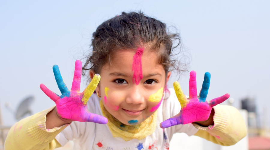 A little girl with paint on her face and hands.