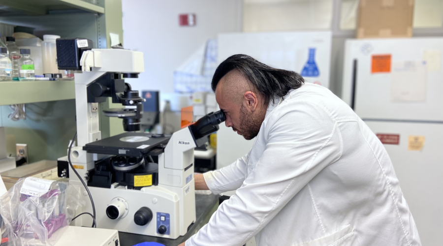 man in lab coat looking into a microscope