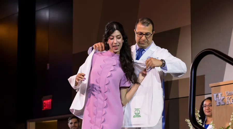 student receives her white coat during a ceremony