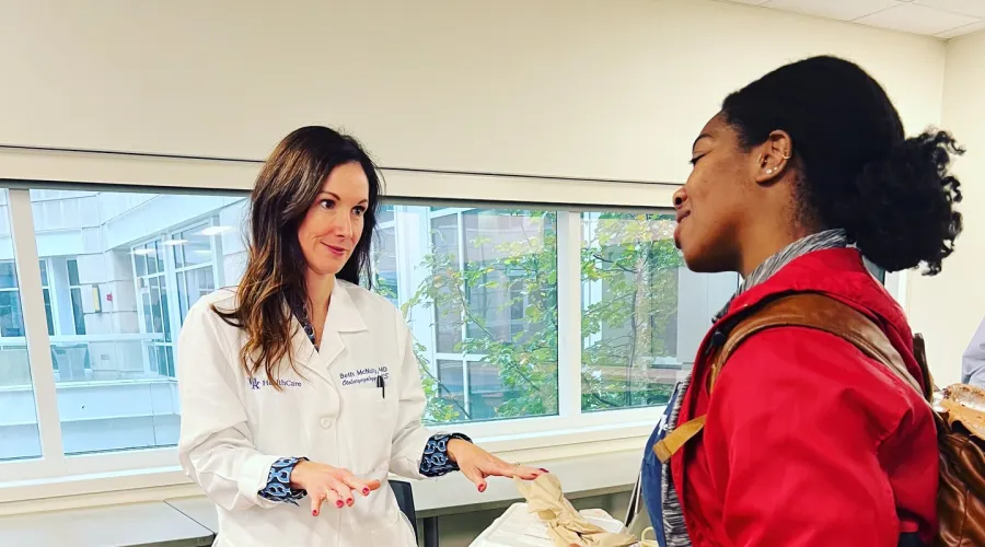 Dr Beth McNulty in white coat talking to a medical student.
