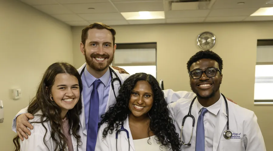 4 medical students pose in white coats