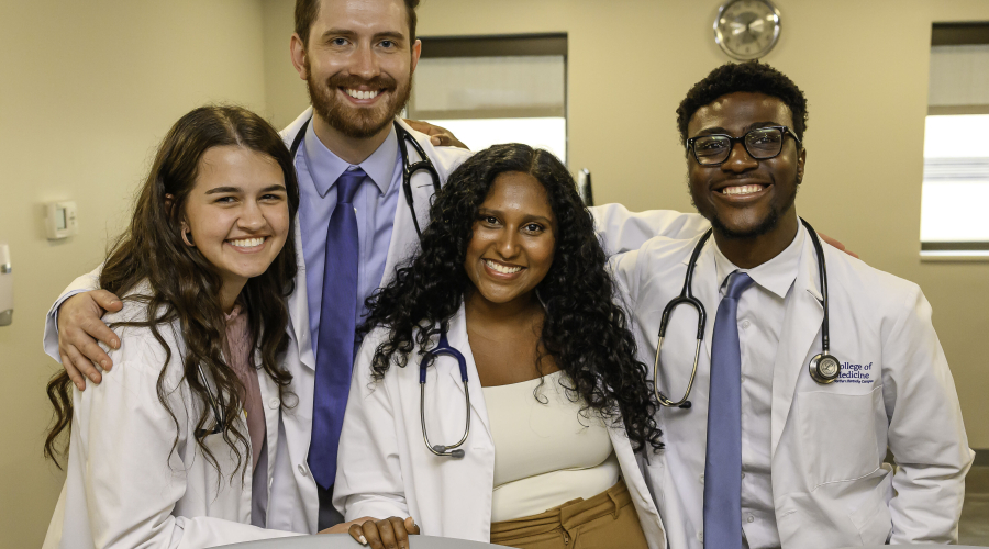 4 medical students pose in white coats