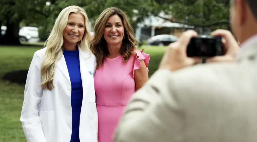 a medical student in a white coat gets her photo taken with a family member at the white coat ceremony