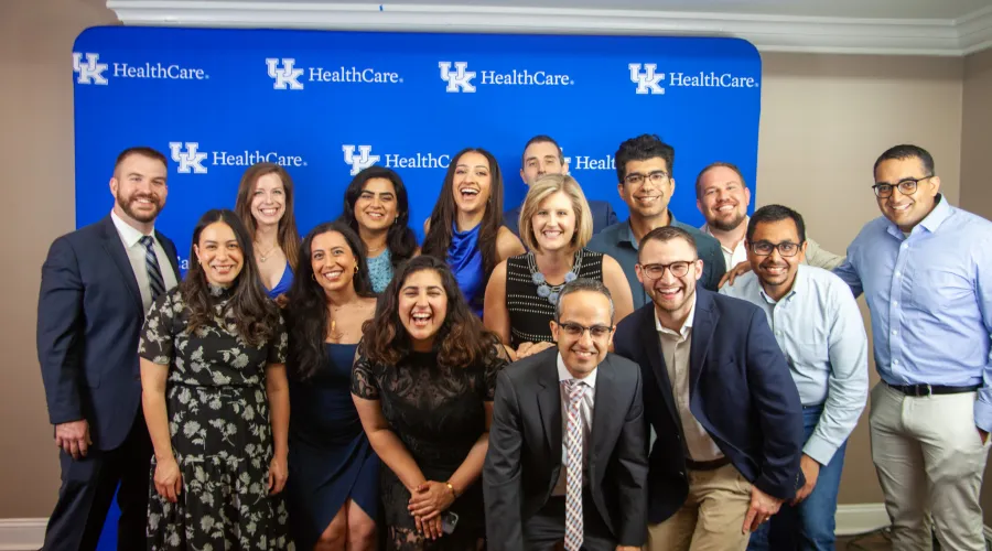 2025 fellows gathered in front of a UK blue wall.