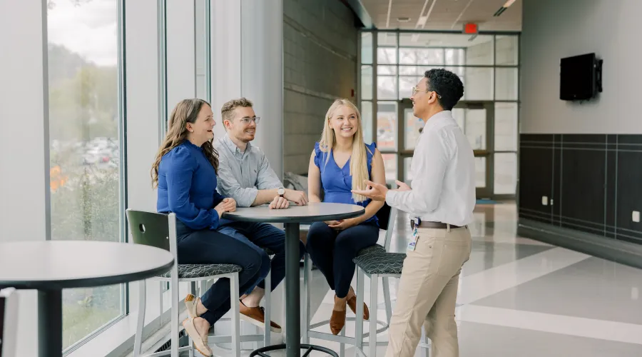 students around a table by a wall of large windows