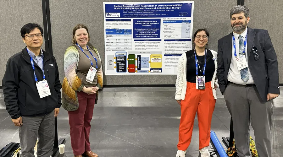 Infectious Diseases fellows pose with a poster during a poster presentation