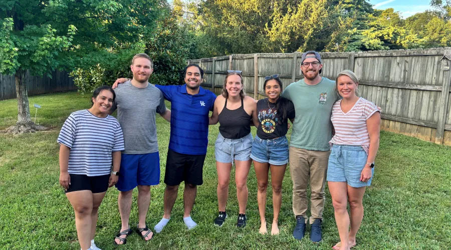A group of track participants stand in a line for a photo outside