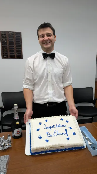 Picture of Dr Elmore holding a cake that says, "Congratulations Dr. Elmore".