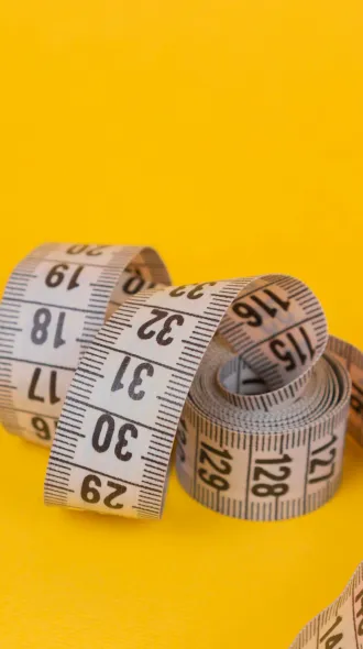 A flexible tape measure against a yellow background.