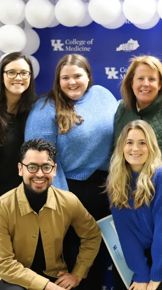 Office of Strategic Communication team poses for group photo in front of blue banner up