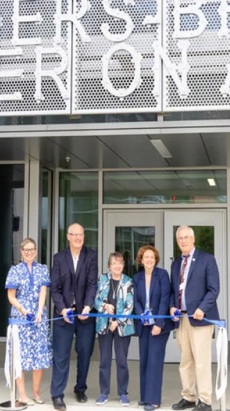 Sanders-Brown faculty cutting a blue ribbon at the grand reopening of their building.