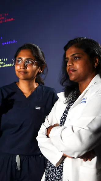 Dhanya Gorty, MD and Rani Priyanka Vasireddy, MD observing a virtual wall of code.
