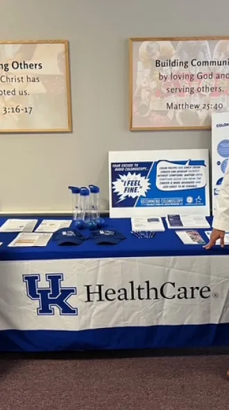 Two doctors in white coats stand flanking a table covered in informational material