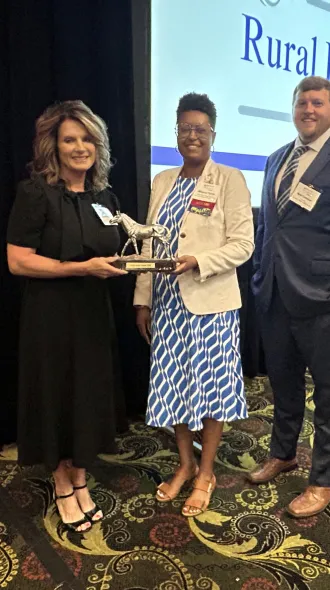 KRMC CEO/CNO Susie Morgan poses with KORH's Matt Coleman and Medina Tipton while accepting the award.