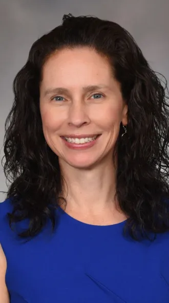 Portrait photo of a woman with shoulder-length brown hair wearing a royal blue sleeveless blouse