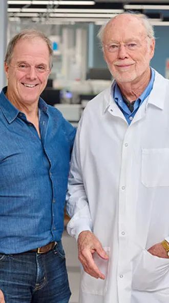 Bill Haney, documentary director, and Phil Sharp standing in Dr. Sharp's lab.