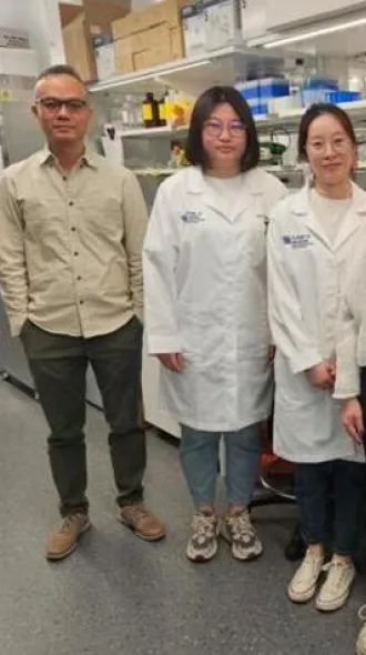 Fong with members of his lab, standing in front of their lab station. Conveying a unified presence.