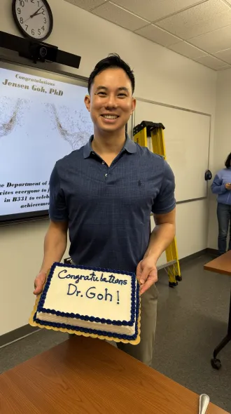 Jensen Goh holds his congratulatory cake for earning his PhD. 