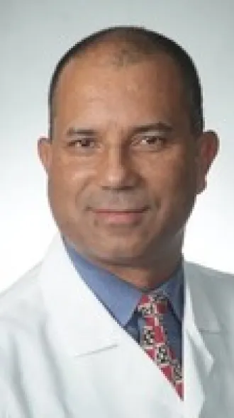 A headshot of Hender Rojas in a white coat