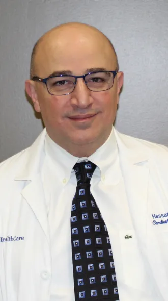 Headshot of Dr. Hassan Reda wearing a white coat and tie in front of a gray background