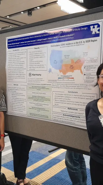 Two women standing on opposite sides of a research poster 