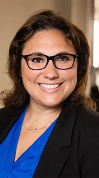 Dr. Elizabeth Rhodus, a brunette woman in glasses smiling, wearing a blue blouse under black blazer. 