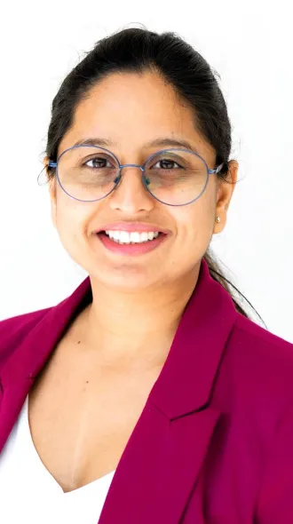 Headshot of Ila Mishra in a pink suit jacket