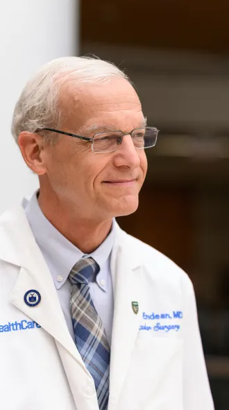Dr. Rick Endean is  in his UK surgery white coat looking away to the right of the camera with a genial smile.