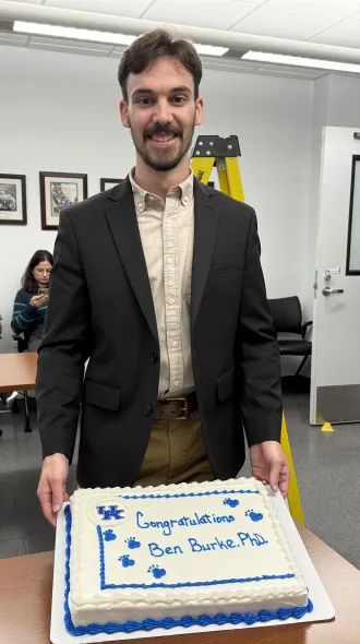 Dr. Burke poses with his congratulatory cake during his defense celebration. 