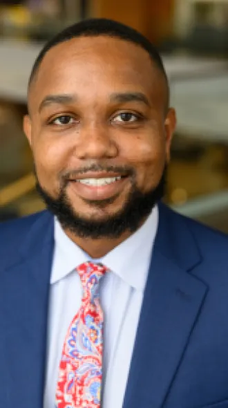Headshot of Justin Xavier Moore in a blue suit